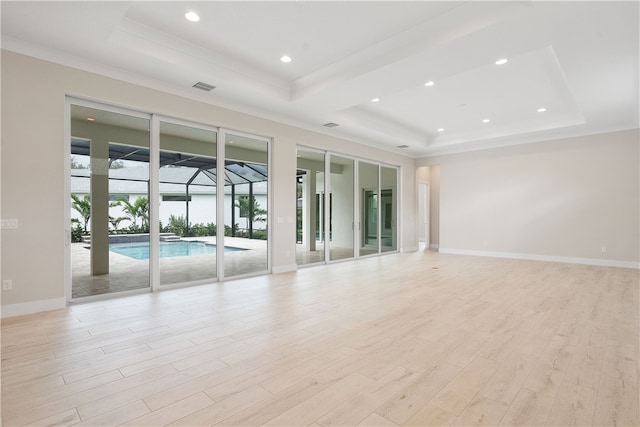 empty room featuring a raised ceiling, crown molding, and light hardwood / wood-style floors