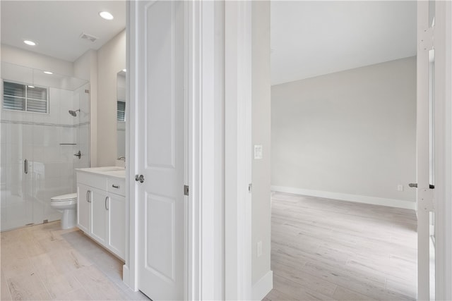 bathroom with a shower with door, vanity, hardwood / wood-style floors, and toilet