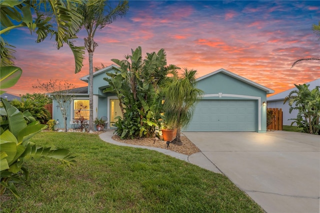 view of front of property with concrete driveway, a lawn, an attached garage, and stucco siding