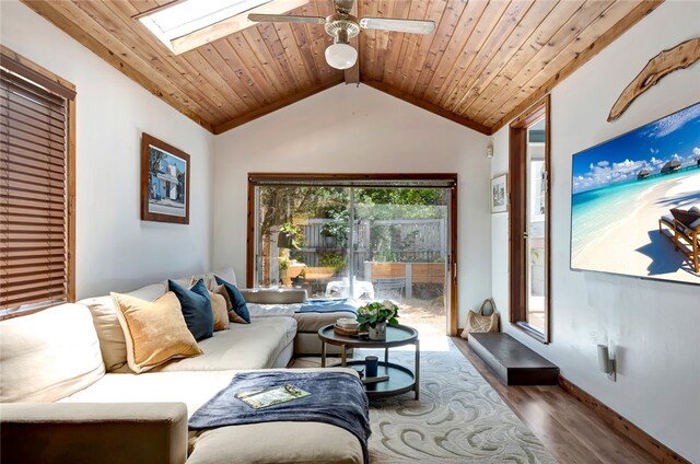 living room featuring vaulted ceiling with skylight, ceiling fan, wood-type flooring, and wooden ceiling