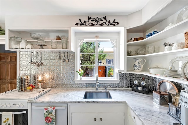 kitchen featuring light stone countertops, backsplash, stainless steel dishwasher, sink, and white cabinetry