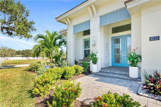 9215 Orchid Cove Cir, Vero Beach, FL 32963 - entrance to property featuring stucco siding, french doors, and a yard