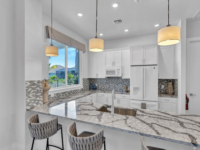 kitchen featuring white appliances, decorative light fixtures, and white cabinetry