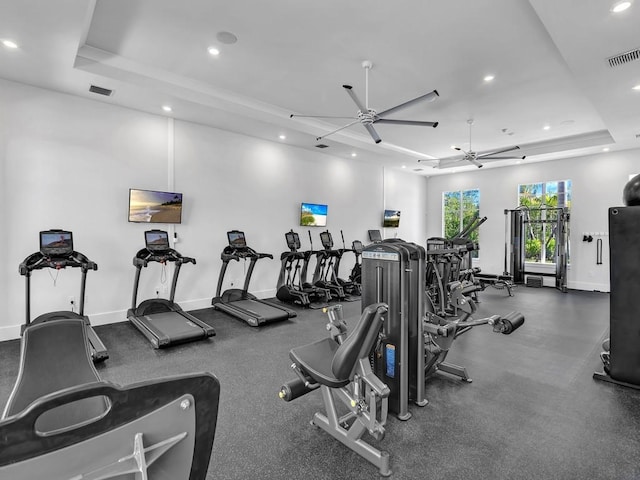 exercise room with a raised ceiling and ceiling fan