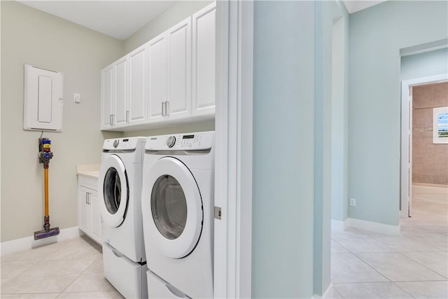 clothes washing area featuring washer and clothes dryer, light tile patterned flooring, cabinets, and electric panel