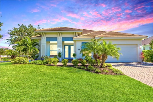 view of front of home featuring a lawn, a garage, and french doors