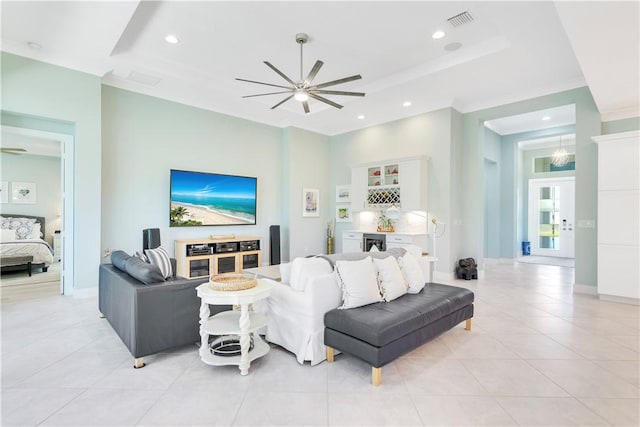 living room featuring a raised ceiling, ceiling fan, and light tile patterned floors