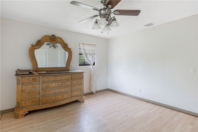 bedroom featuring ceiling fan, light hardwood / wood-style floors, and a textured ceiling