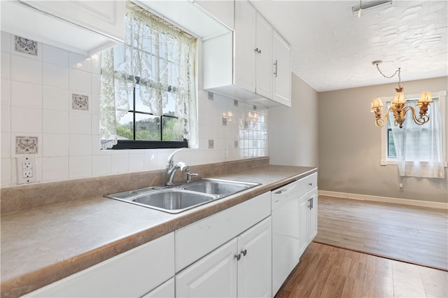 kitchen with dishwasher, sink, hardwood / wood-style flooring, decorative light fixtures, and white cabinetry