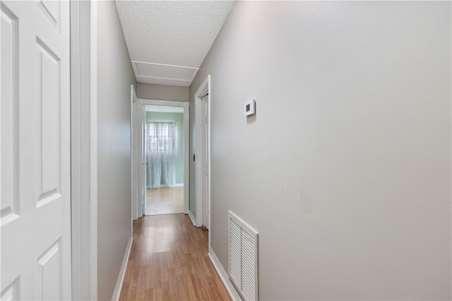 hallway featuring a textured ceiling and light hardwood / wood-style floors