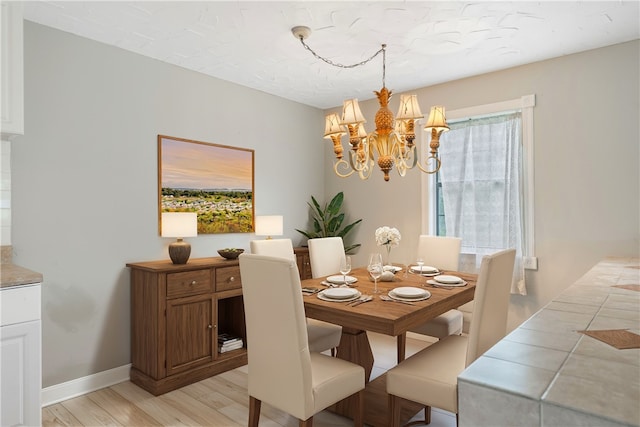 dining area with light hardwood / wood-style flooring and a notable chandelier