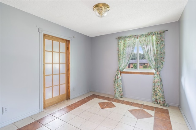 spare room featuring light tile patterned floors and a textured ceiling