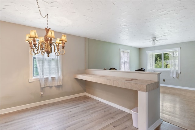 interior space featuring ceiling fan with notable chandelier and light wood-type flooring