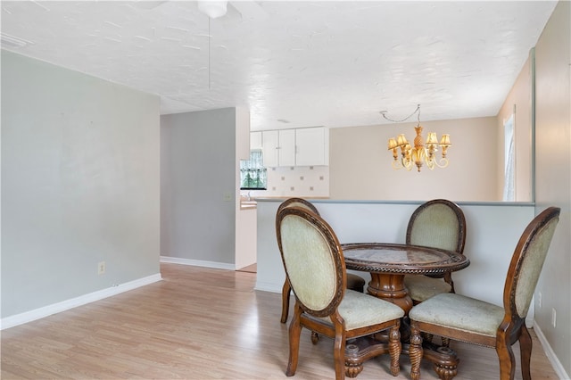 dining room with light hardwood / wood-style floors, a textured ceiling, and an inviting chandelier