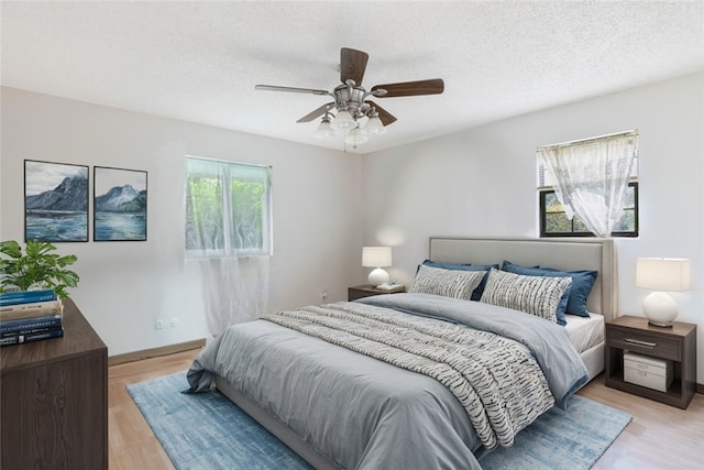 bedroom with ceiling fan, light hardwood / wood-style floors, and a textured ceiling