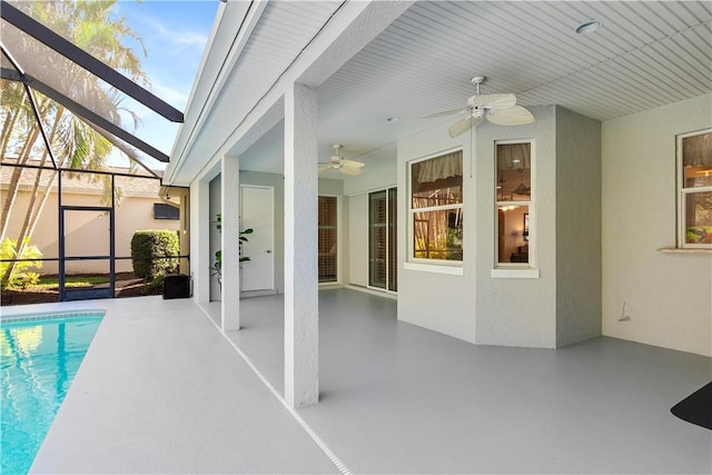 view of swimming pool featuring glass enclosure, a patio, and ceiling fan