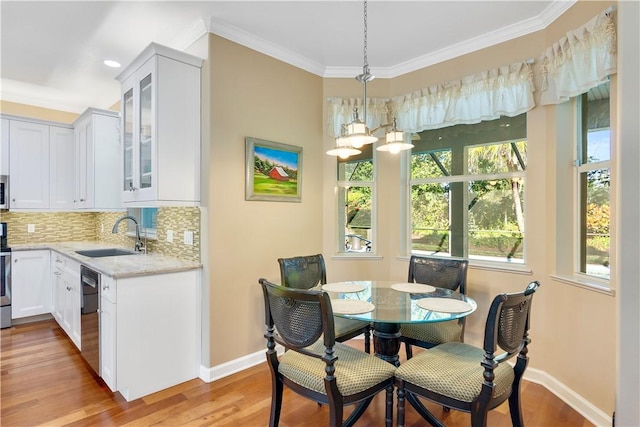 dining space featuring sink, crown molding, and light wood-type flooring