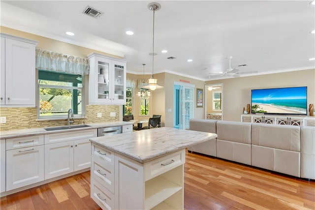 kitchen with light stone countertops, white cabinets, decorative light fixtures, decorative backsplash, and sink