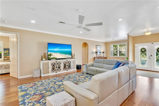 living room with ceiling fan, ornamental molding, french doors, and light wood-type flooring