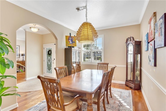 dining area with light hardwood / wood-style floors and ornamental molding