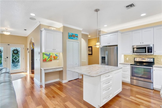 kitchen with a center island, appliances with stainless steel finishes, white cabinetry, decorative backsplash, and pendant lighting