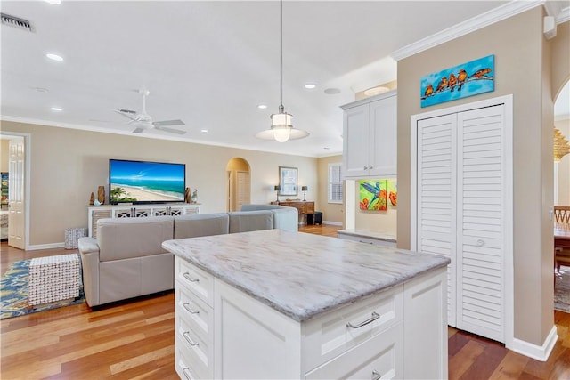 kitchen with light hardwood / wood-style floors, white cabinetry, a center island, and pendant lighting