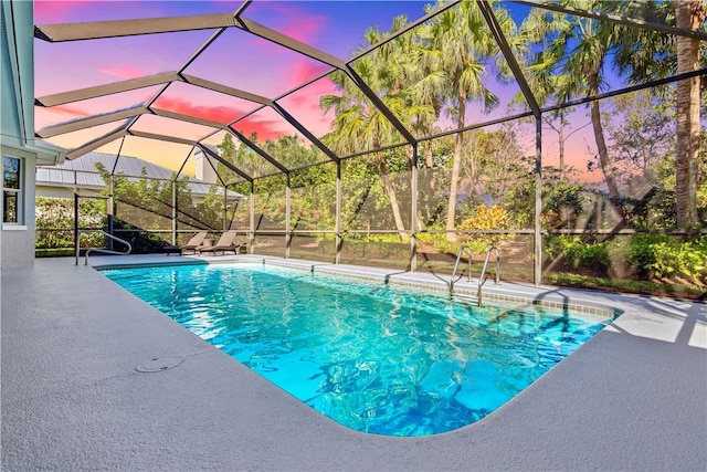 pool at dusk featuring glass enclosure and a patio area