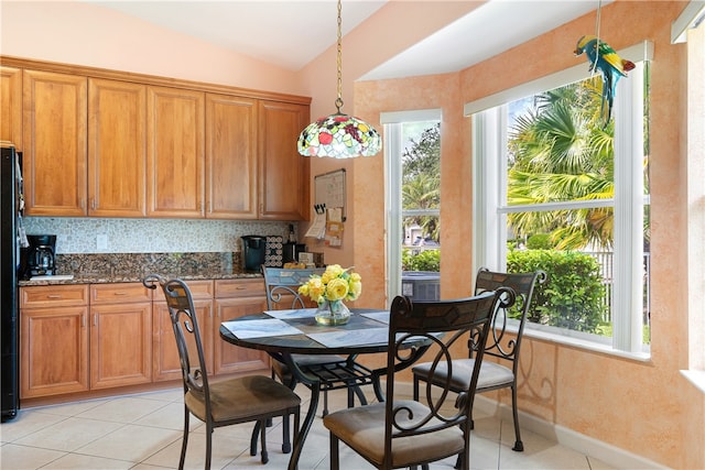 tiled dining room featuring vaulted ceiling