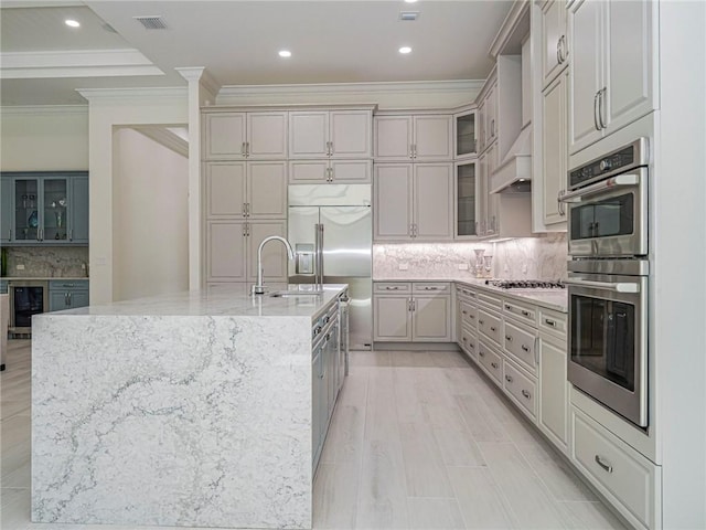 kitchen with appliances with stainless steel finishes, a kitchen island with sink, sink, and wine cooler