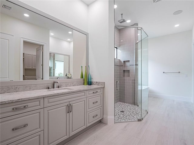 bathroom with hardwood / wood-style flooring, vanity, and a shower with shower door