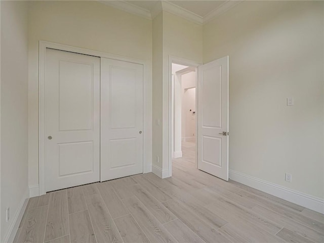 unfurnished bedroom with crown molding, light hardwood / wood-style flooring, and a closet