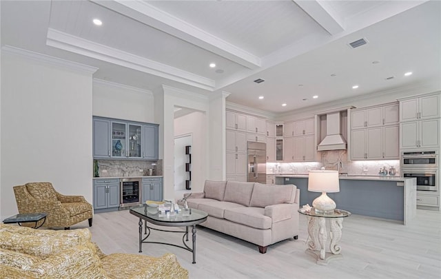 living room with beam ceiling, crown molding, indoor wet bar, light hardwood / wood-style flooring, and beverage cooler