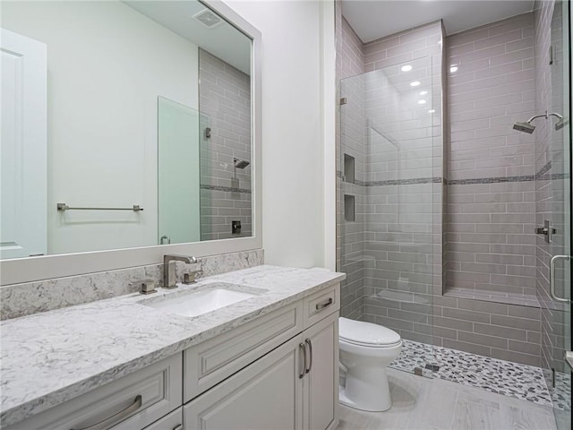 bathroom with vanity, toilet, and a shower with door