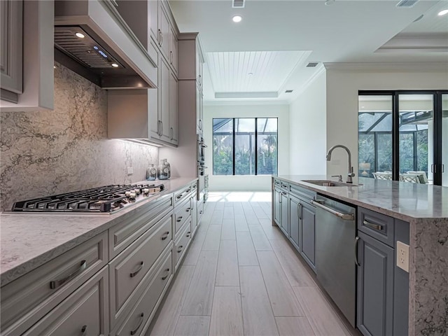 kitchen with premium range hood, sink, gray cabinetry, a tray ceiling, and stainless steel appliances