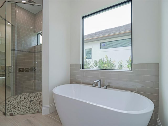 bathroom with a healthy amount of sunlight, separate shower and tub, tile patterned flooring, and tile walls