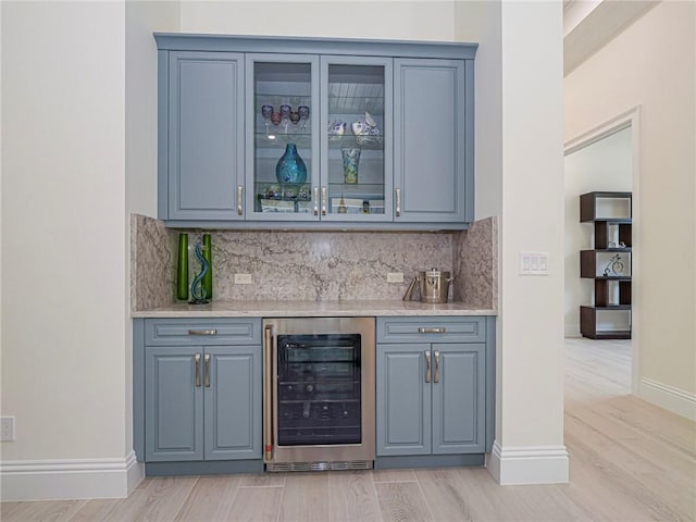 bar featuring tasteful backsplash, beverage cooler, and light hardwood / wood-style floors