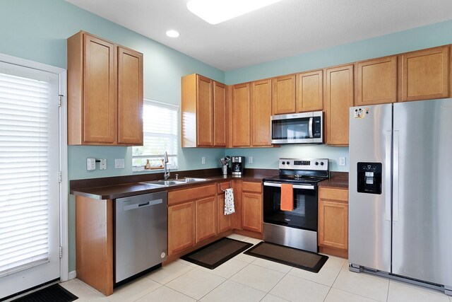 kitchen with appliances with stainless steel finishes, sink, and light tile patterned flooring