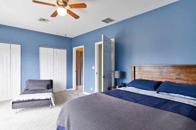 carpeted bedroom with ceiling fan and two closets