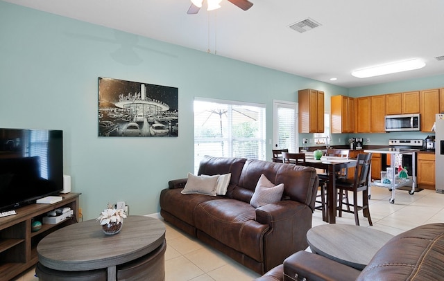 living room featuring light tile patterned flooring, ceiling fan, and sink