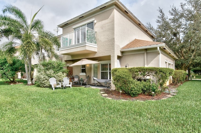 rear view of property with a lawn, a patio, and a balcony