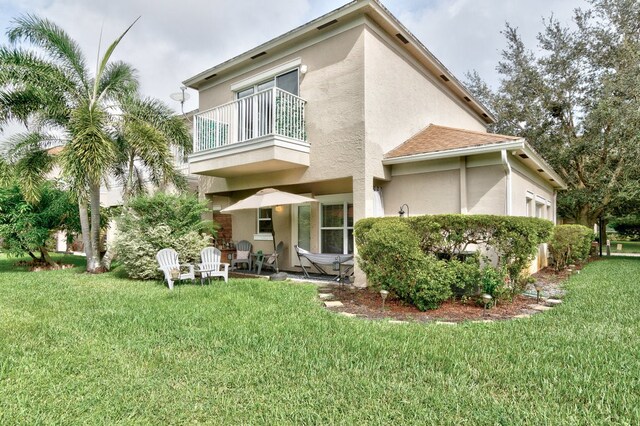 rear view of property with a lawn, a patio, and a balcony