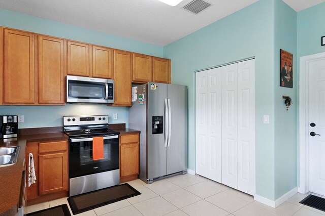 kitchen with light tile patterned flooring, a textured ceiling, sink, and appliances with stainless steel finishes