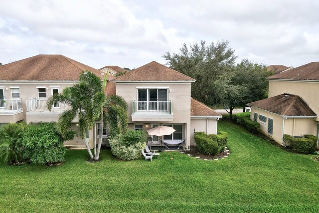 back of house with a yard and a balcony