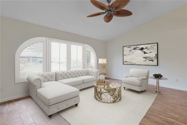 living room featuring a textured ceiling, light wood-type flooring, ceiling fan, and lofted ceiling