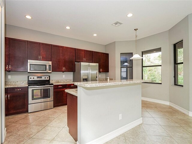 kitchen with a center island, hanging light fixtures, stainless steel appliances, light stone counters, and light tile patterned floors