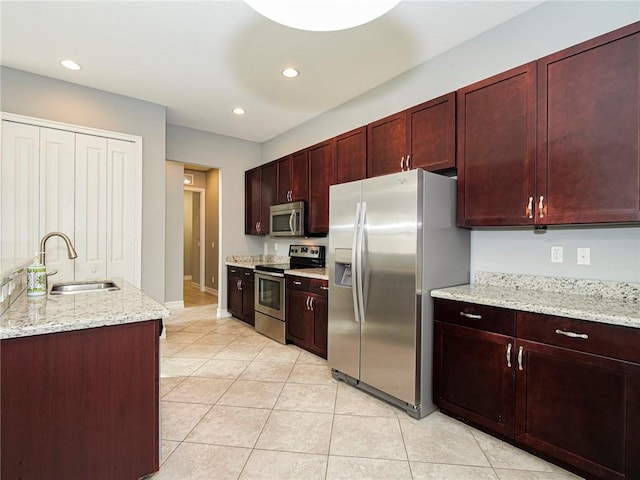 kitchen featuring light stone countertops, appliances with stainless steel finishes, light tile patterned floors, and sink