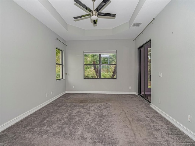 carpeted spare room featuring a tray ceiling and ceiling fan