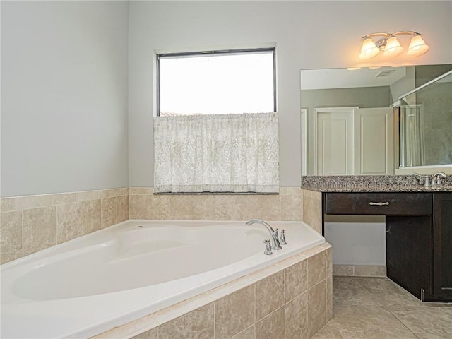 bathroom with tile patterned flooring, vanity, and tiled bath