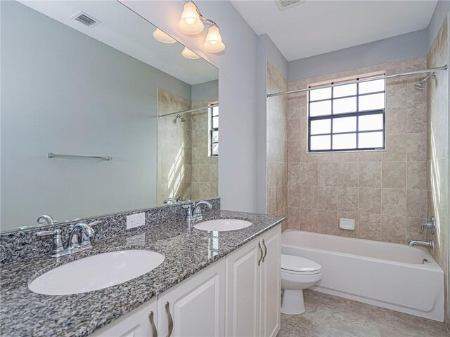 full bathroom with vanity, tiled shower / bath combo, and toilet