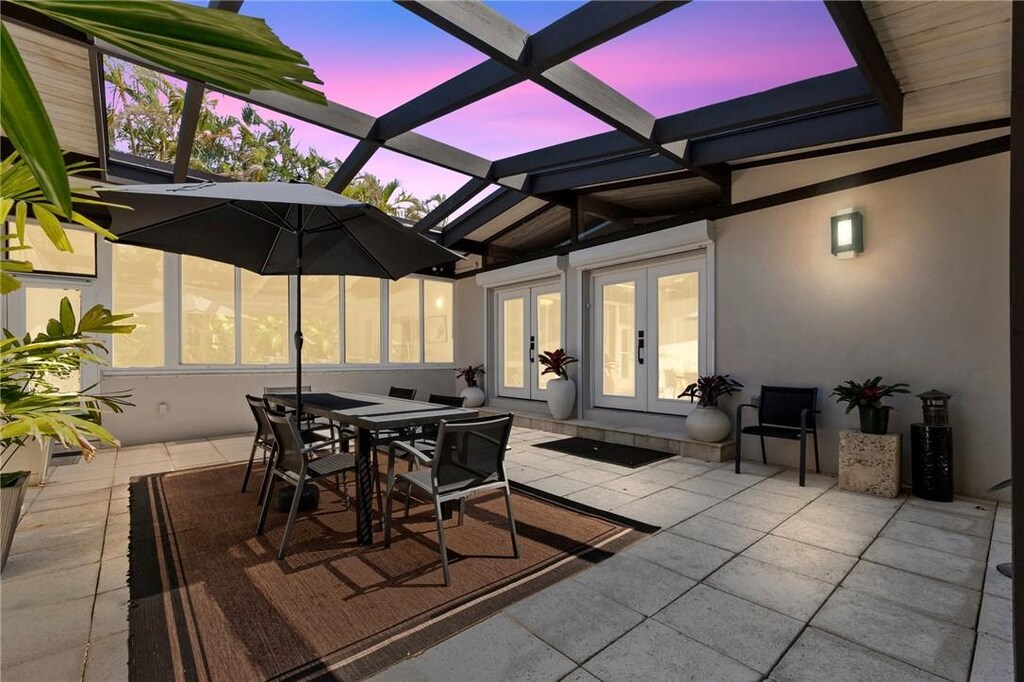 3526 Mockingbird Dr, Vero Beach, FL 32963 - patio terrace at dusk with glass enclosure and french doors